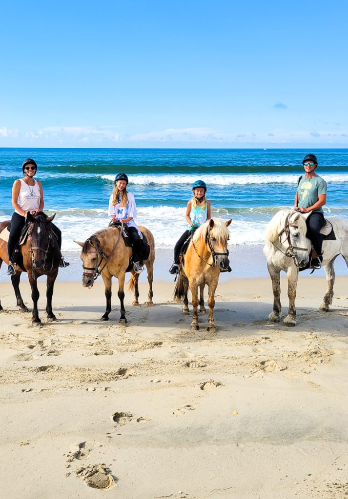 Family of four horse riding on the beach in the Outer Banks of North Carolina