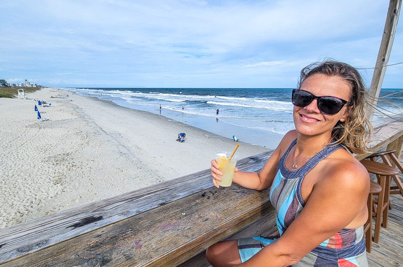 Caroline Makepeace having a cocktail on a pier overlooking Carolina Beach