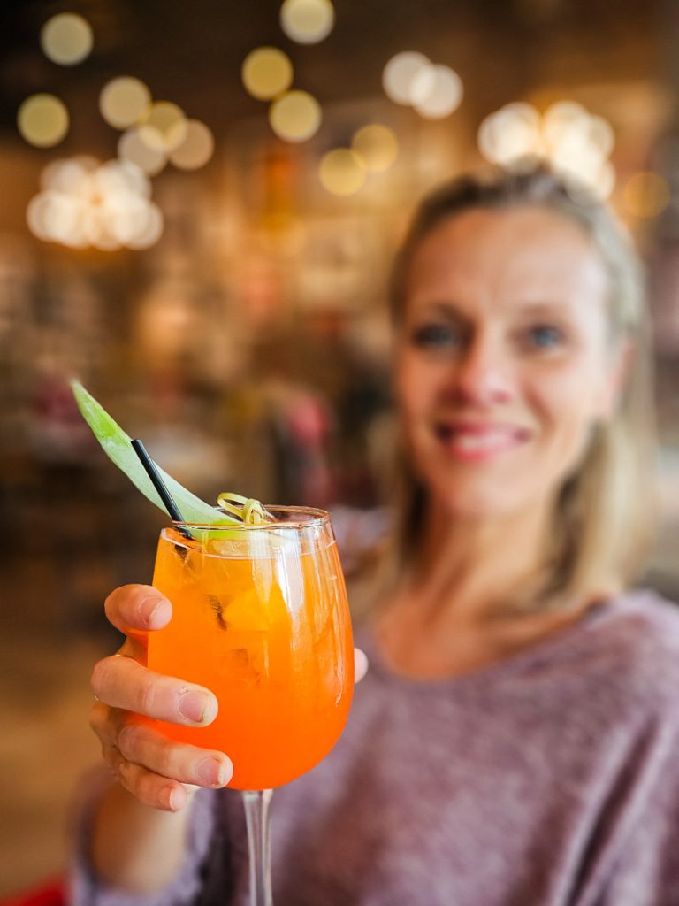 Lady holding up an orange cocktail