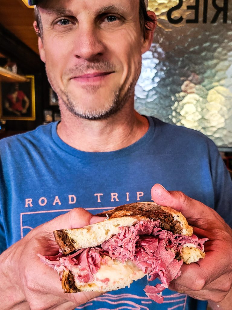 Man holding a Reuban sandwich.