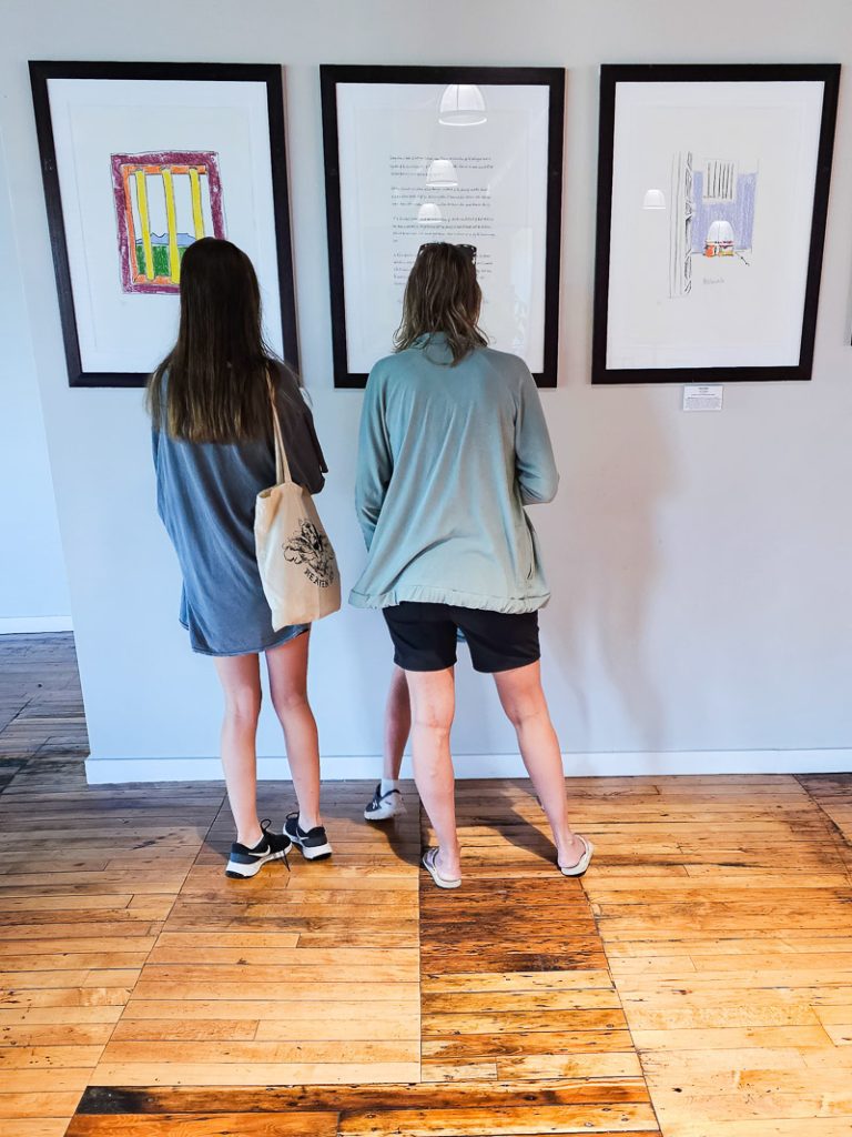 Two people looking at drawings on a wall