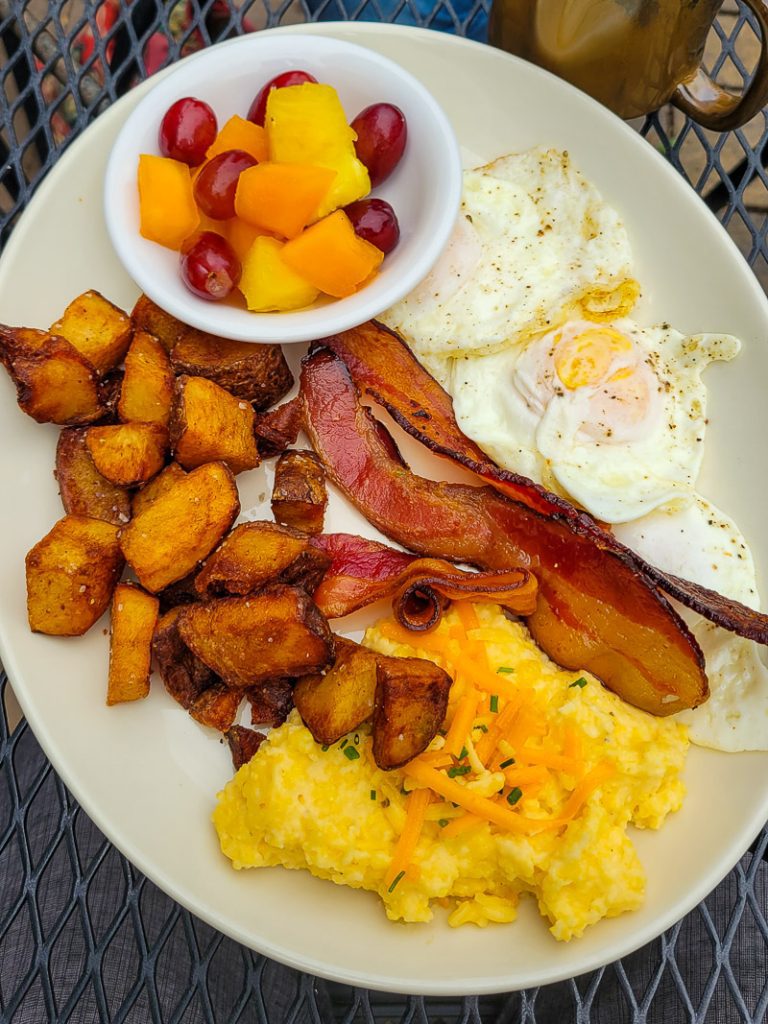 Bacon and eggs and fruit on a plate