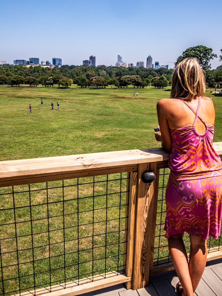 Lady standing at a fence overlooking a park