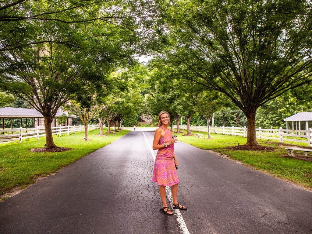 Lady standing in middle of street underneath trees