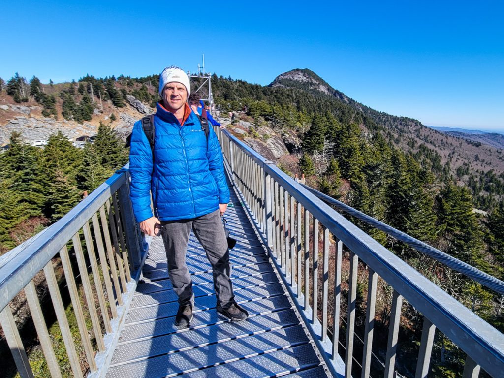 Man standing on a bridge with a mountain view