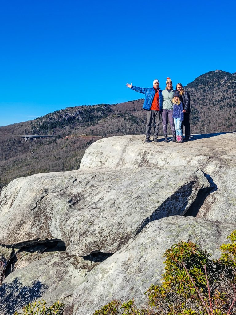 Family of four standing on rock ledge in the mountains