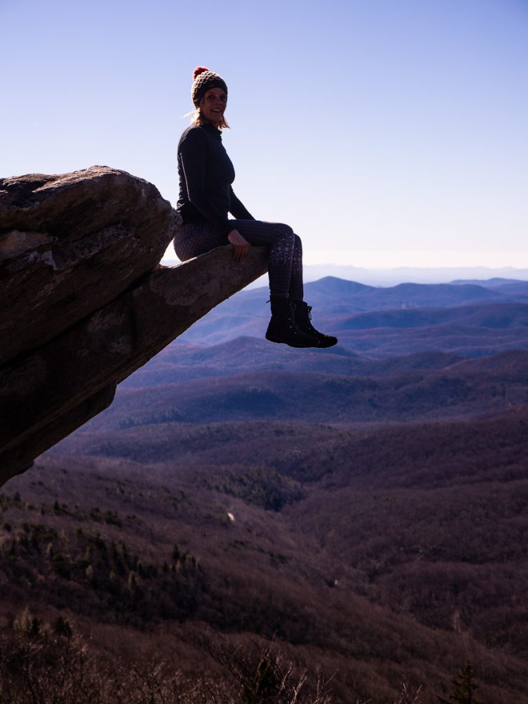 Woman sitting on rock ledge in the mountains