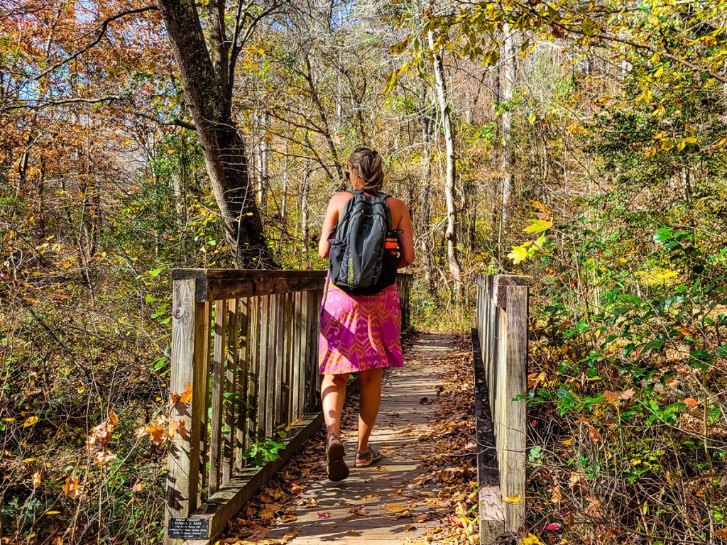 Woman hiking a nature trail through the woods with colorful leaves.