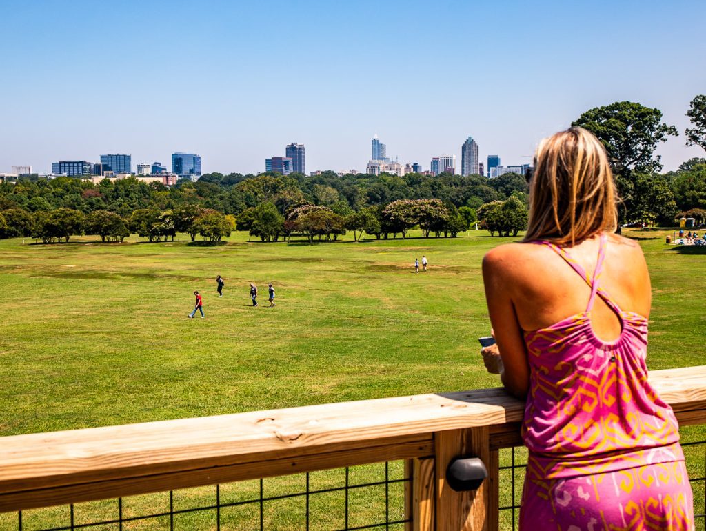 Woman overlooking a city park from a wooden deck