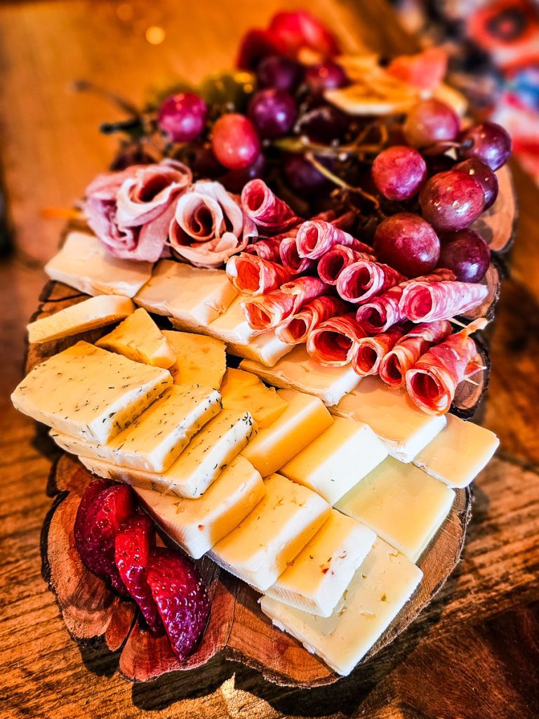 Cheeses and meats and fruits on a wooden board