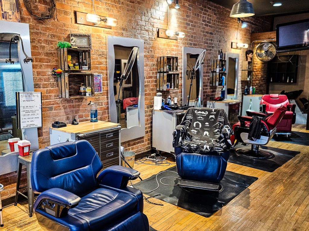 Inside a barber shop with chairs, mirrors and a wooden floor