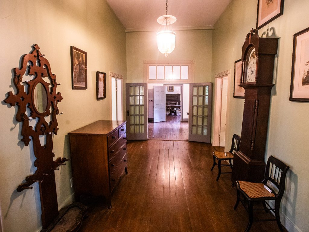 Antique furniture on display in a hallway with wood floors