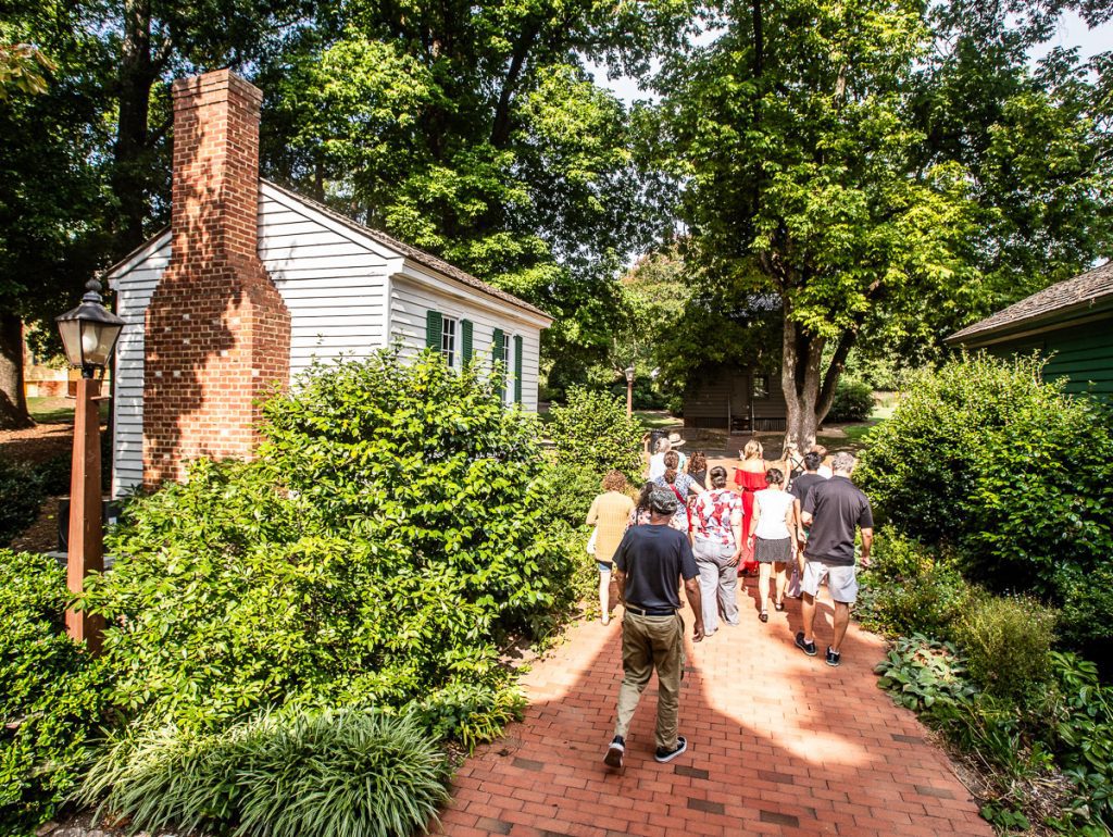 People walking down a brick path next to a white cottage