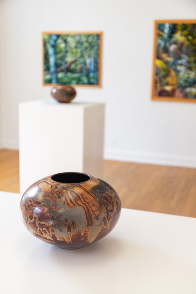 pottery bowl on display in front of paintings on the wall