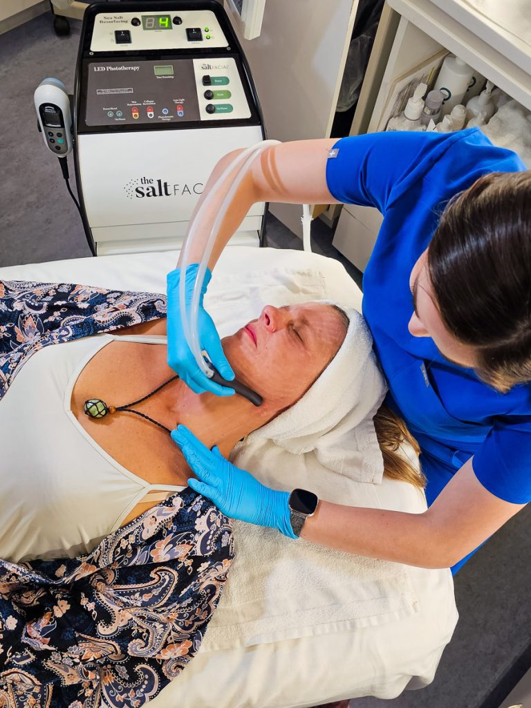 A woman lying down receiving a salt facial from a medical therapist.
