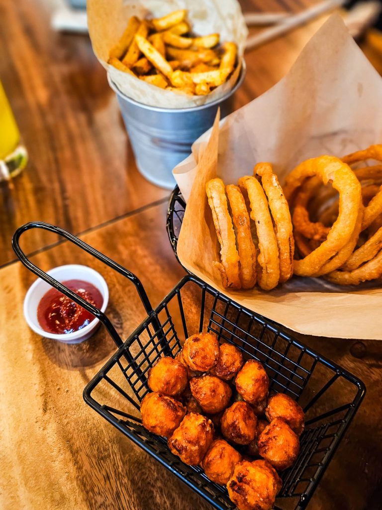Onion rings, fries, and sauce on a table.