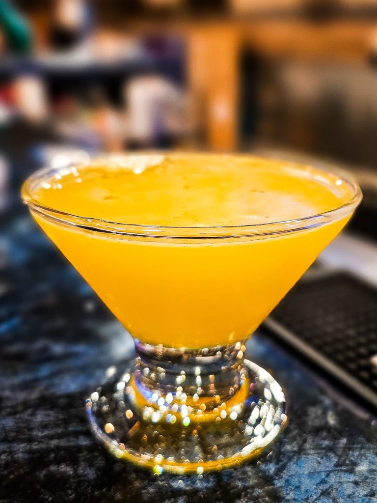 Orange cocktail in a glass on a bar.