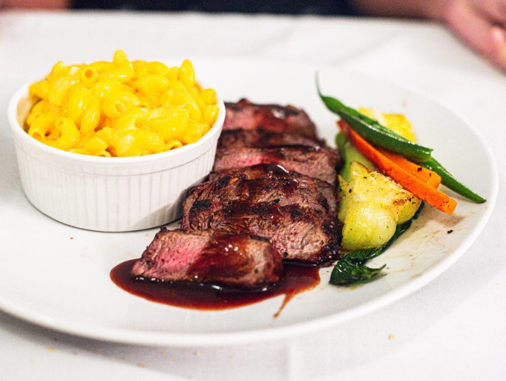 sliced flank steak with mac and cheese and vegetables