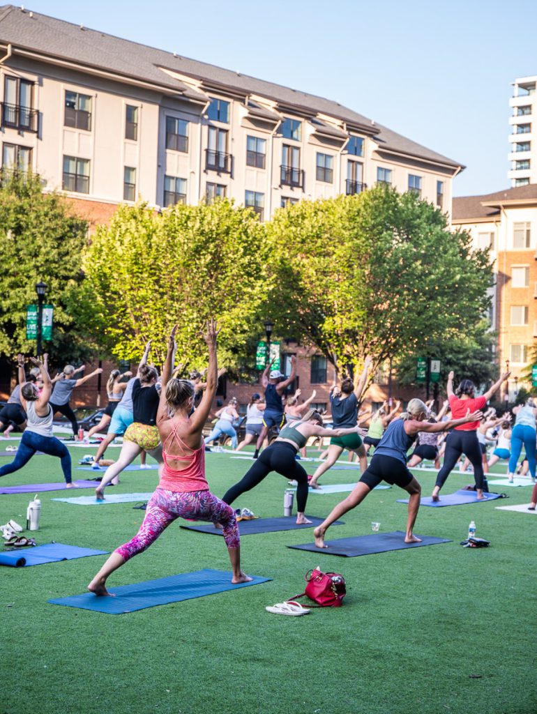 Group of people doing yoga outdoors in a park.