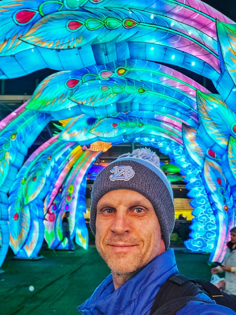 Man standing under an arch of illumined lights.