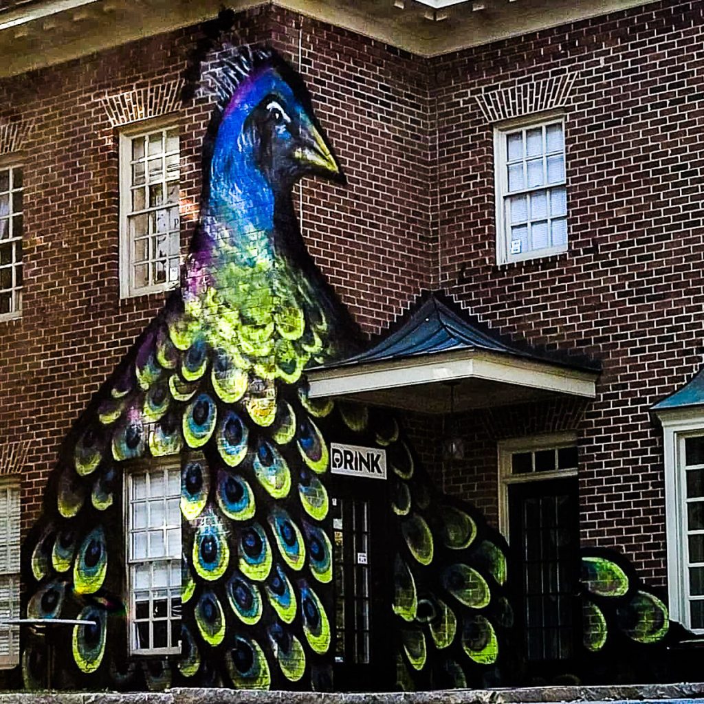 Brick building with a mural of a peacock.