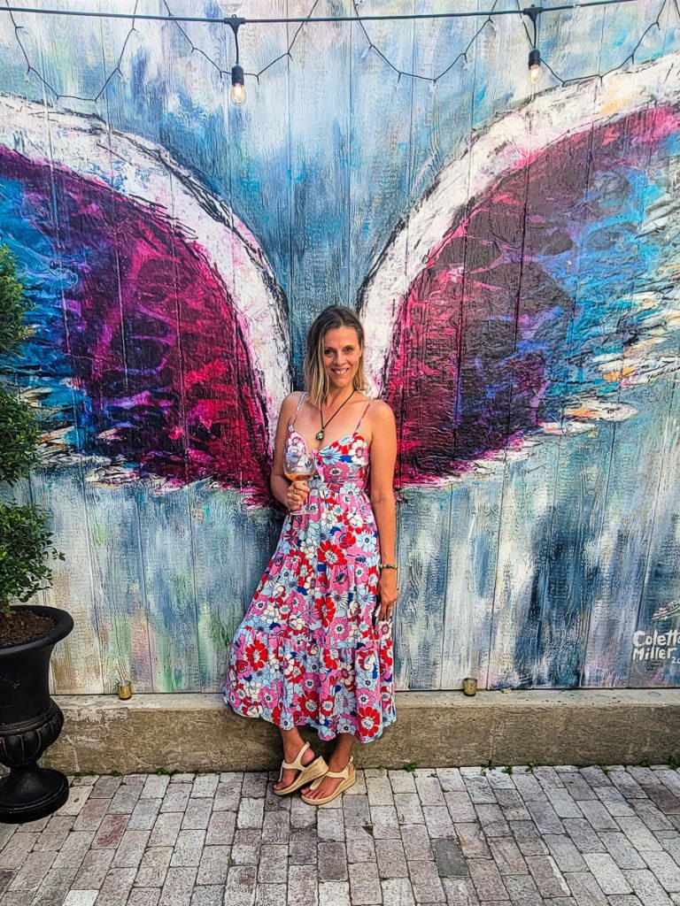 Lady standing in front of a mural of angel wings.