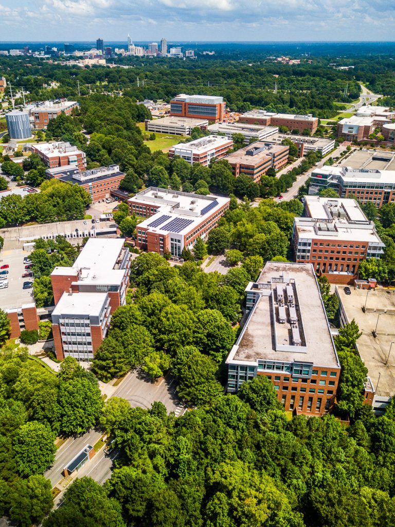 Aerial view of NC State University campus in Raleigh surrounded by green trees.