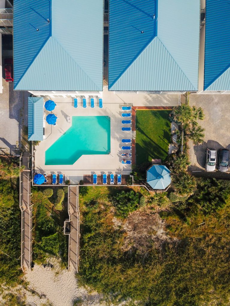 aerial view of hotel swimming pool and rooms with pathway to beach