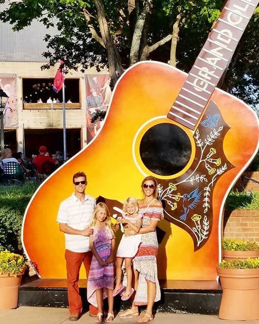 Family standing in front of a giant guitar.