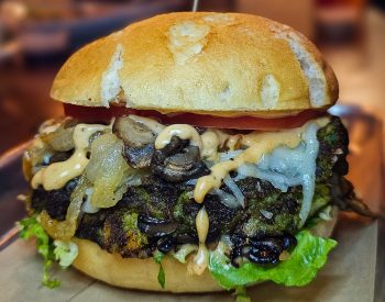 Vegetarian burger with mushrooms, cheese, and lettuce on a bun.