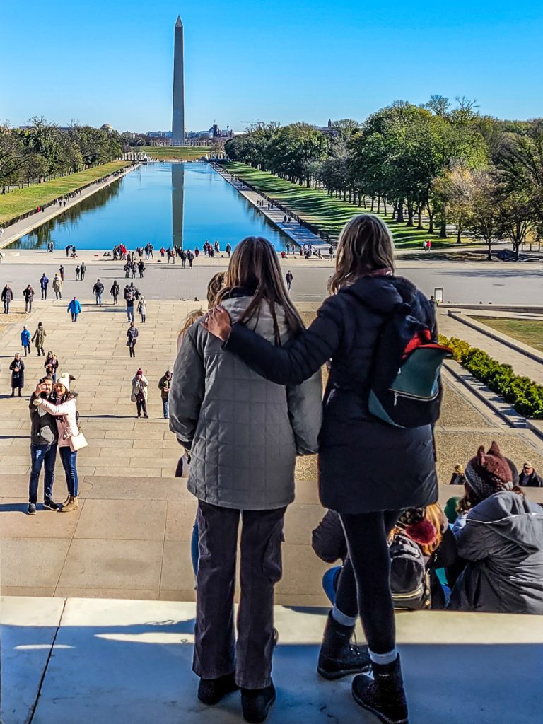 Mom and daughter looking out over a pond and monument in Washington DC.